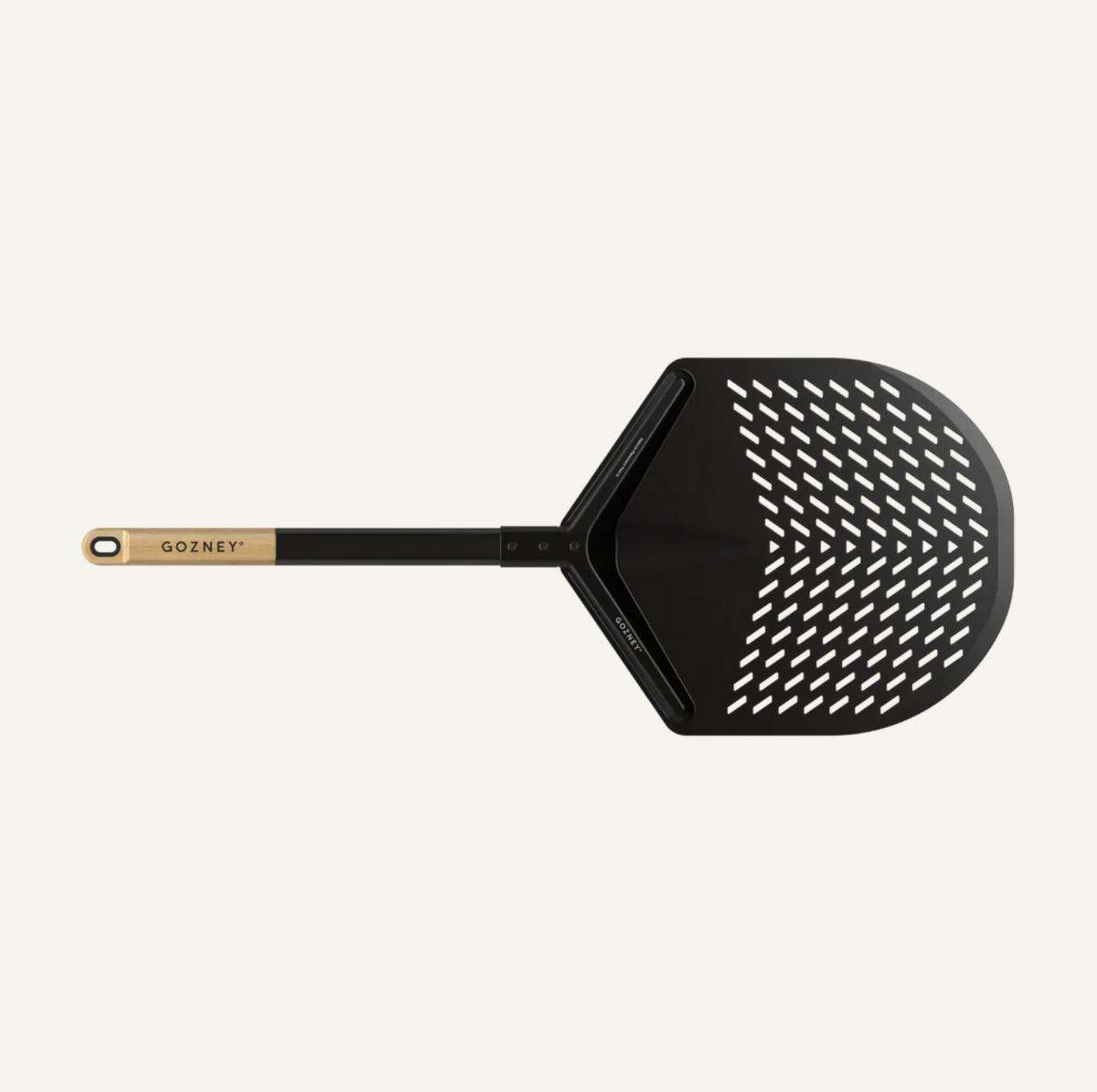 A black pizza peel with a perforated paddle head and a light wood handle, shown on a solid off-white background. The brand name GOZNEY is printed in gold on the handle.
