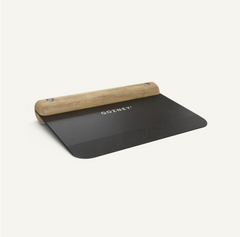 A Gozney pizza cutter with a black rubber blade dough cutter and a light natural wood handle, shown on a clean off-white background.
