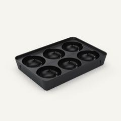 Black silicone mold with six round cavities on a white background
