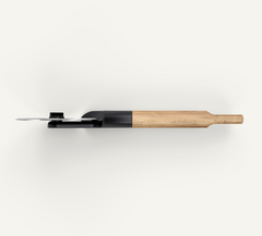 A modern kitchen knife with a black handle and a light natural wood bolster, shown from a top-down perspective on a clean off-white background.